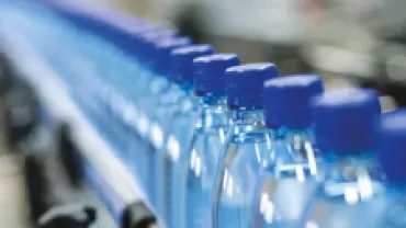 Close-up of a row of blue capped water bottles on a production line.