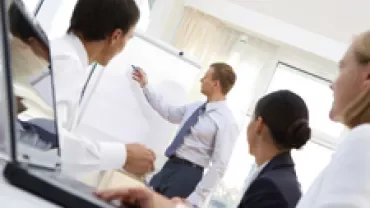 Business meeting with a person presenting on a flip chart to colleagues.