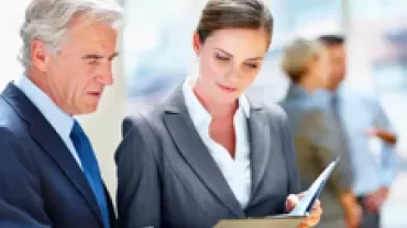 Two professionals reviewing documents in an office.