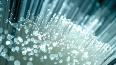 Close-up of illuminated fiber optic cables, glowing with a soft blue light.