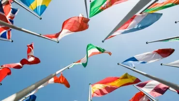 Colorful flags waving against a clear blue sky.