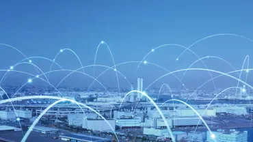 City skyline with blue digital network lines arching above buildings.