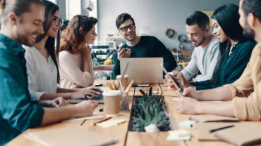Group of people having a discussion around a table in a modern office.