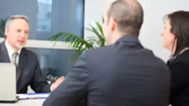 A meeting between three people in an office setting.