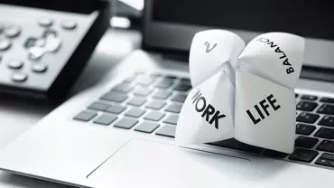 Paper fortune teller with work-life balance theme on a laptop keyboard.